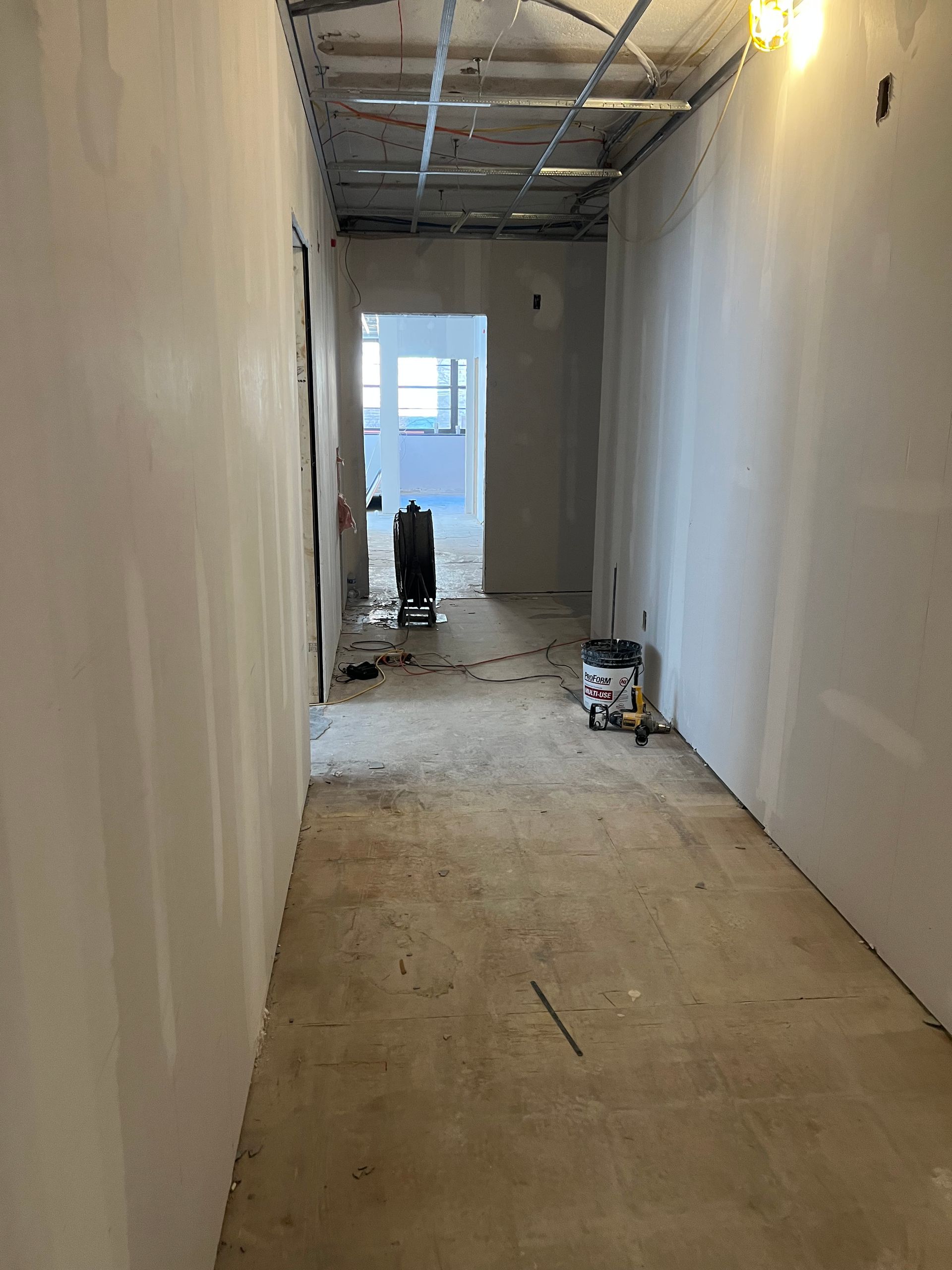 Unfinished hallway with drywall, exposed ceiling, and open doorways, construction site.