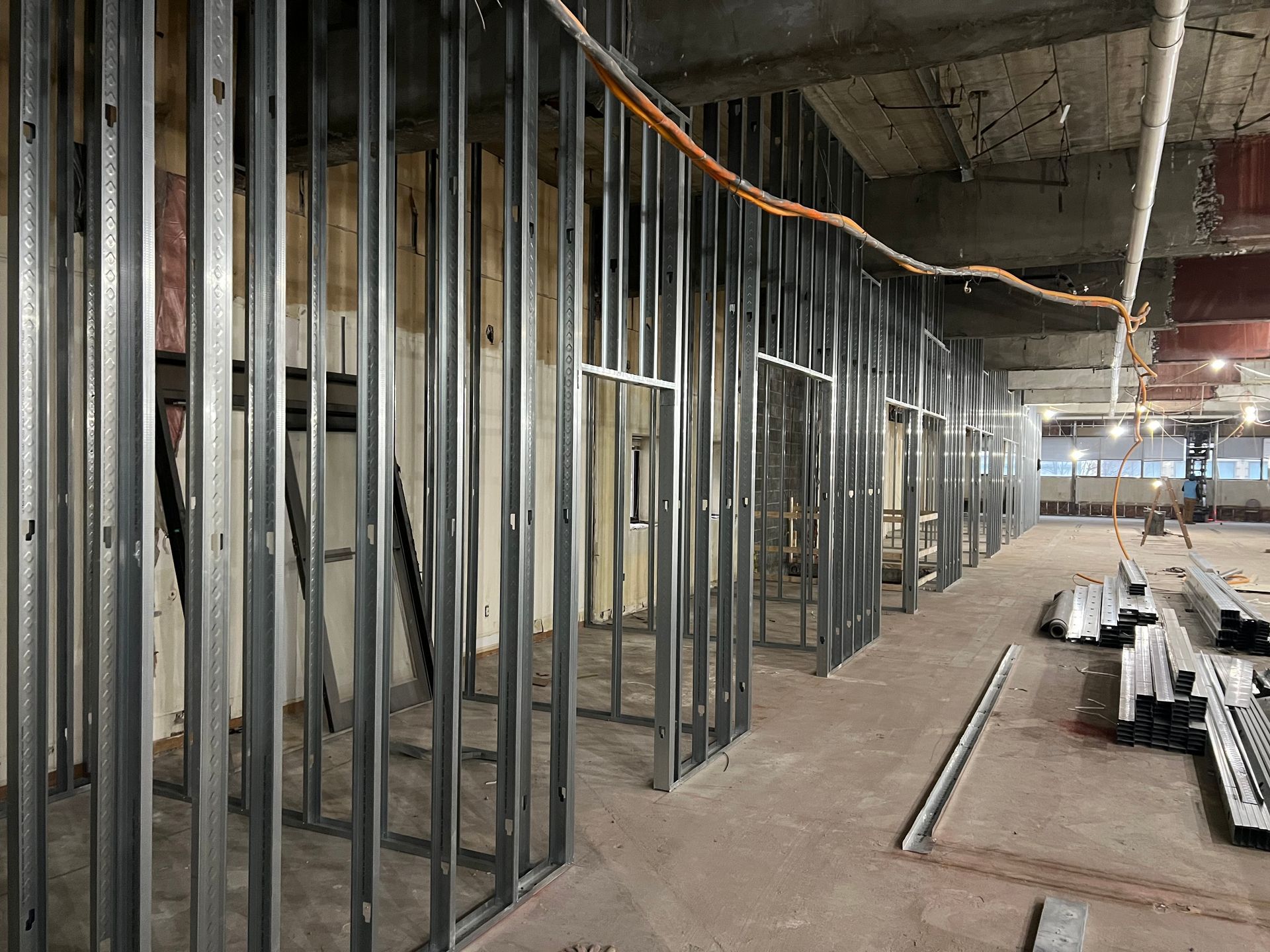 Metal studs frame interior walls under construction, with exposed wiring and concrete ceiling.