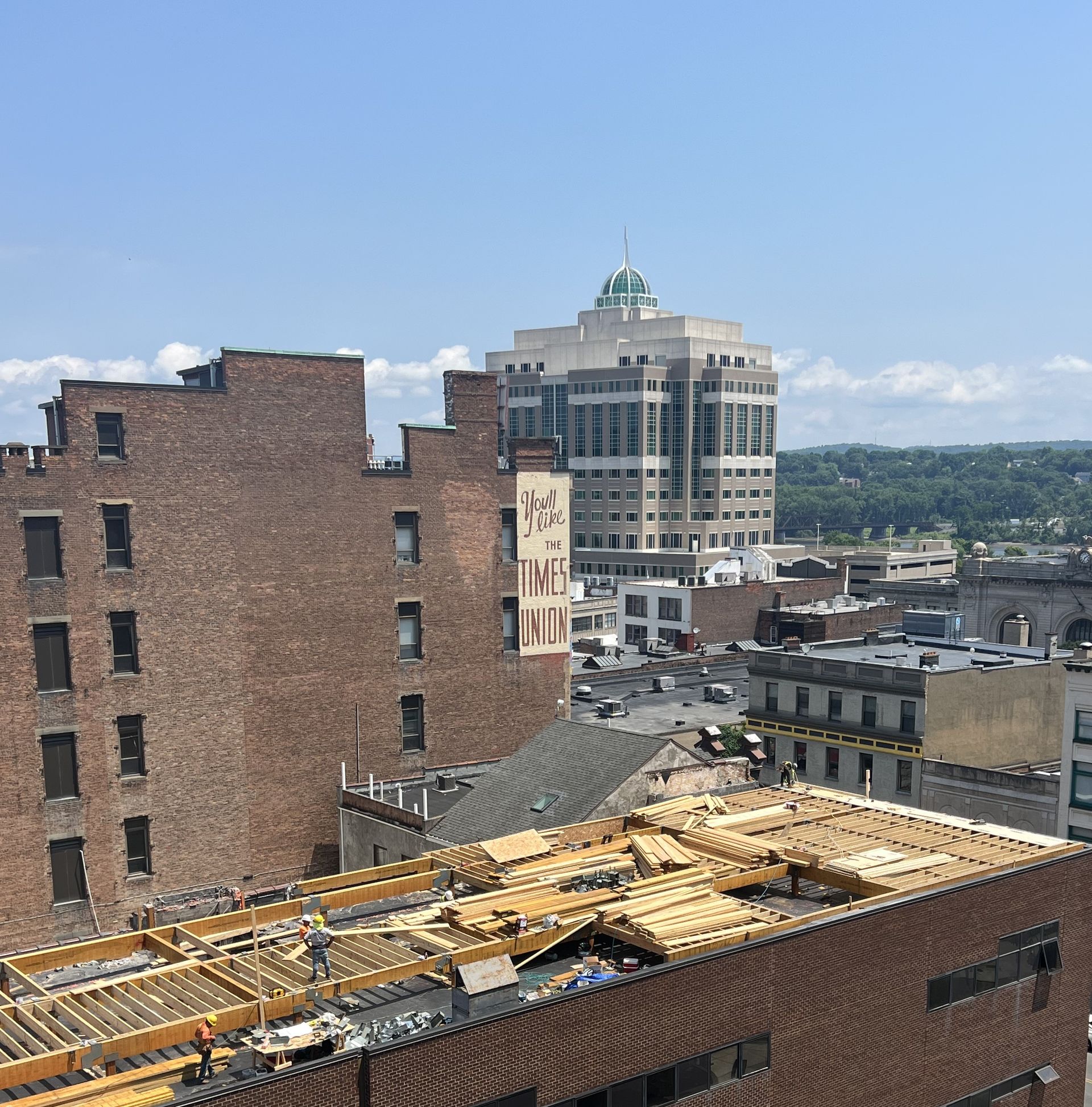Cityscape with brick buildings and a tall office building under a blue sky.