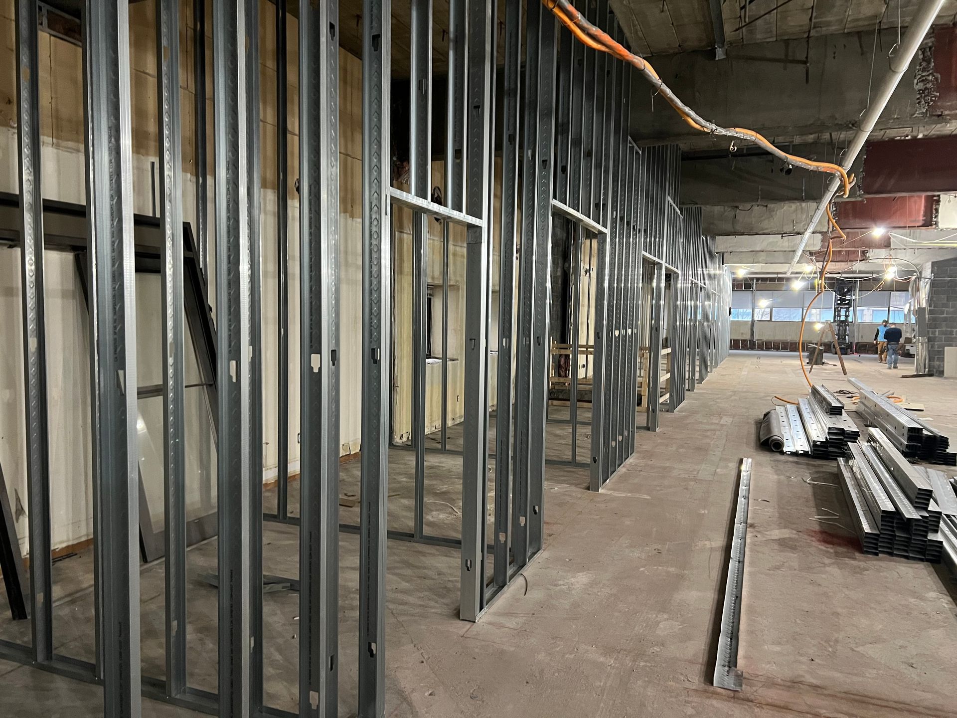 Interior space under construction, metal stud framing for walls and doorways. Concrete floor and ceiling visible.