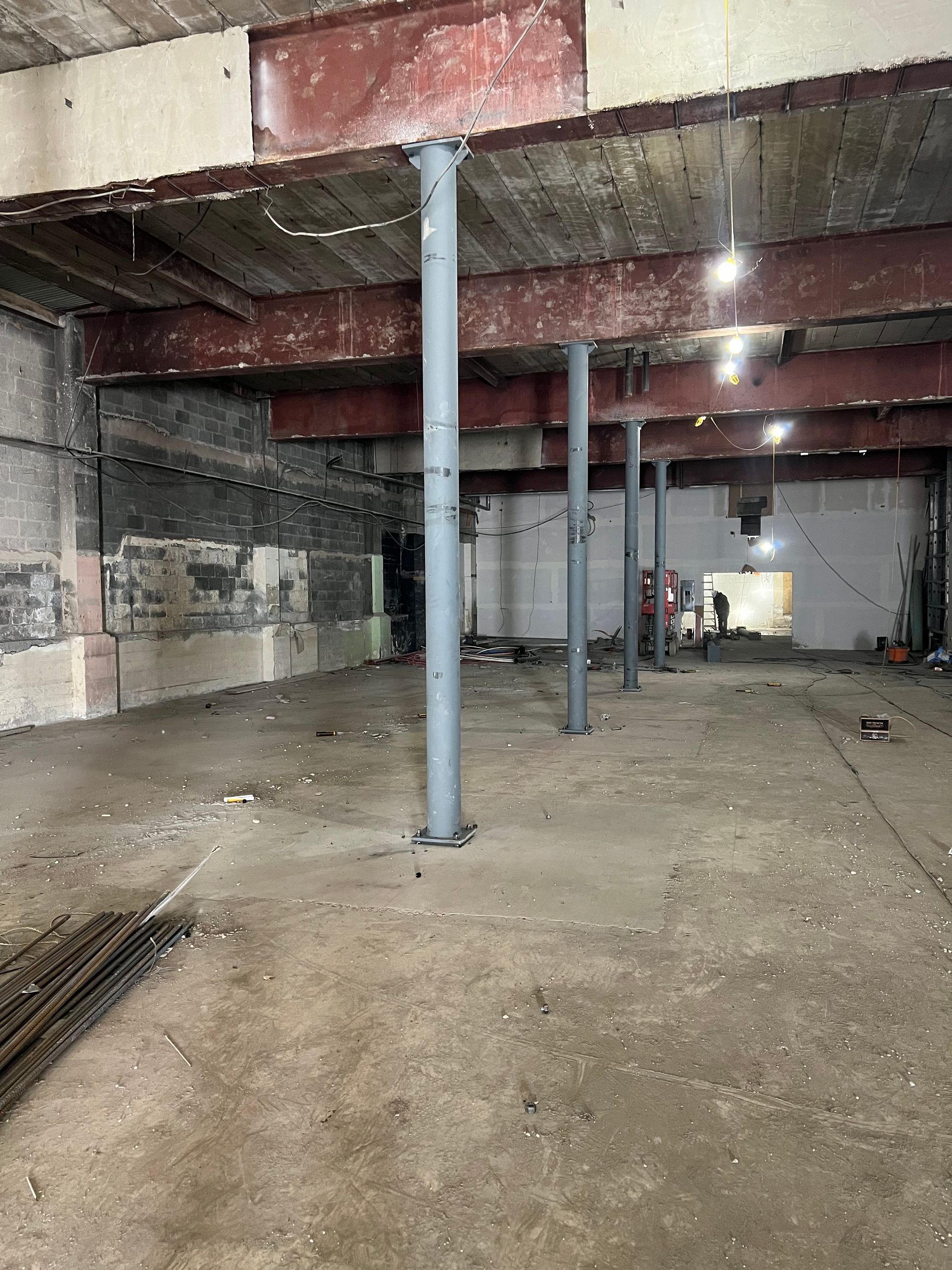 Interior of a large room under construction with support beams, concrete floor, and exposed ceiling.