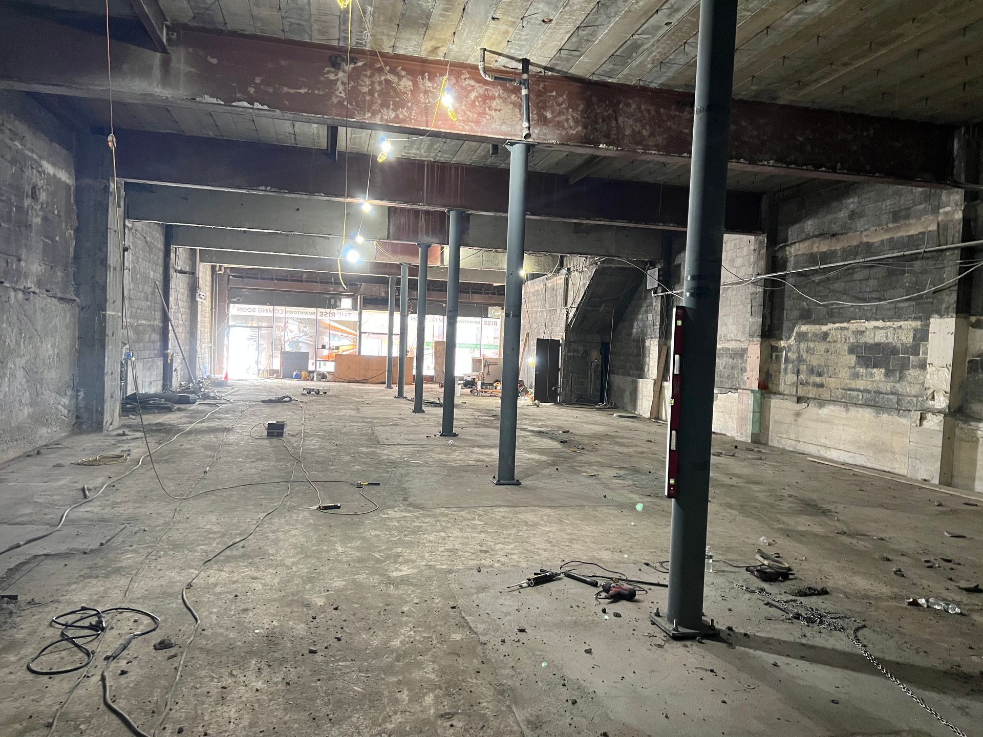 Interior of a building under construction, with steel beams, support columns, and rubble on the floor.