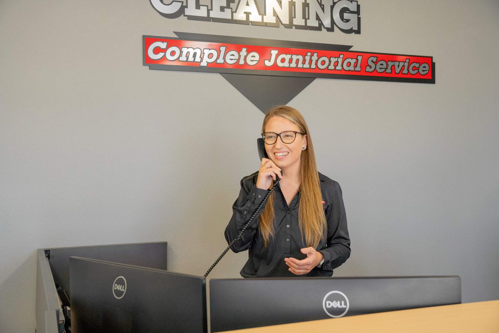 Woman in black shirt on phone at front desk under