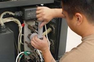 Man working on machine, injecting liquid with a syringe. Inside of a machine with wires.