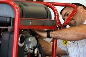 Man fixing a red generator, wearing a watch, in a workshop.
