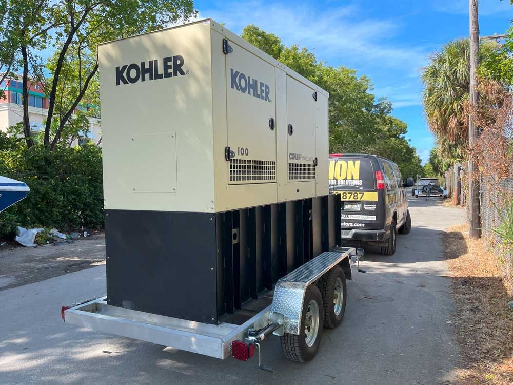 Kohler generator on a trailer, beside a black van on a city street.
