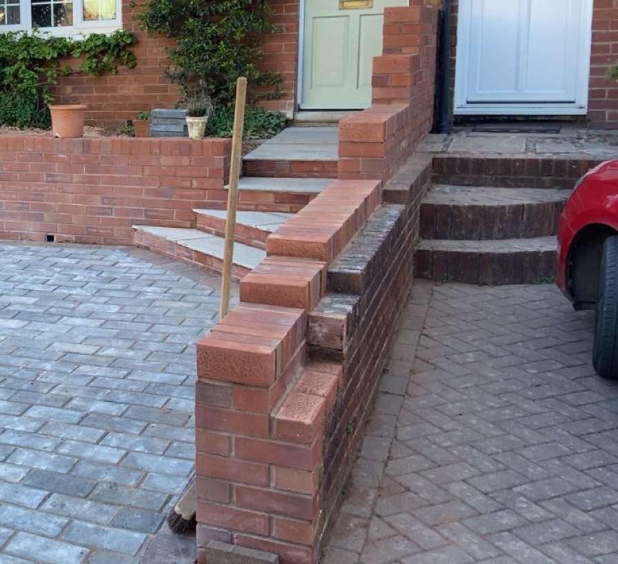 a brick wall built next to a new pathing driveway cleaned and new between two properties 