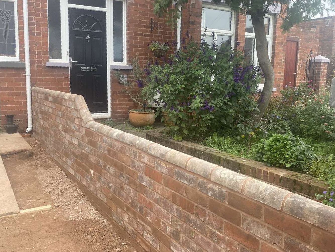 Dyl Boundary Wall a brickwall that has been recently made with a house door in the background of work completed