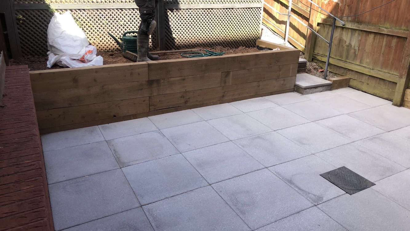 a timber garden wall and new patio outside in the shade