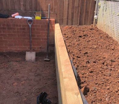 garden wall built by Dyl for Devon Expert Bricklayers in a muddy garden with tools out 