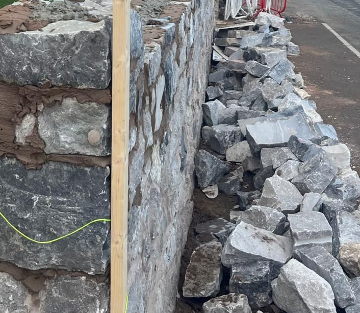 Stone Wall Masonry stone wall being built with stone on the pavement and wooden support on wall