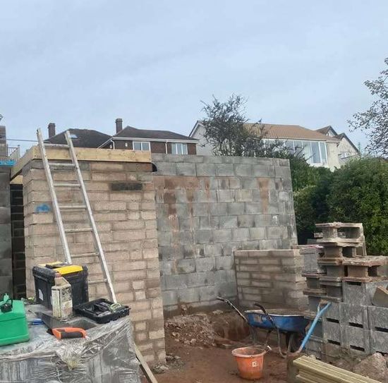 Block Work job completed with load bearing wall and a ladder stood up with tools and wheel barrow on the floor