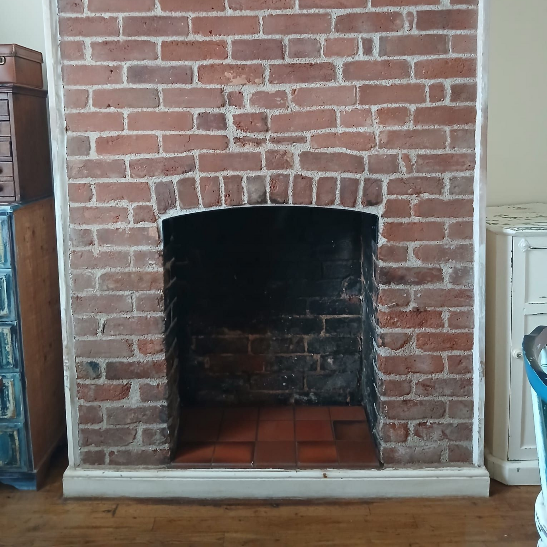 Brick fireplace with arched opening, red-brown bricks, white trim, and a dark interior.