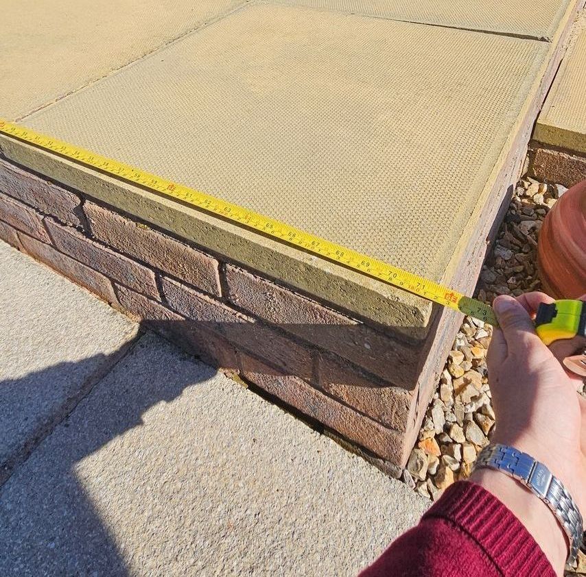 Tape measure over a patio on a sunny day by a man with a silver watch on