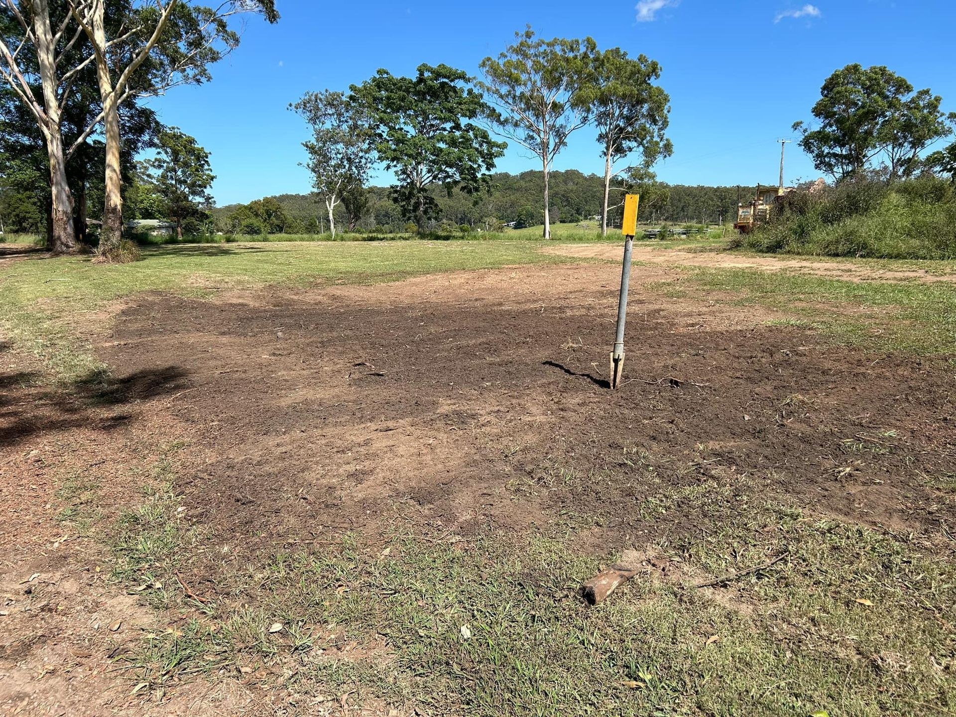 A Dirt Field with Trees in The Background and A Yellow Pole in The Middle — All One Arb Tree Service In Bonny Hills, NSW