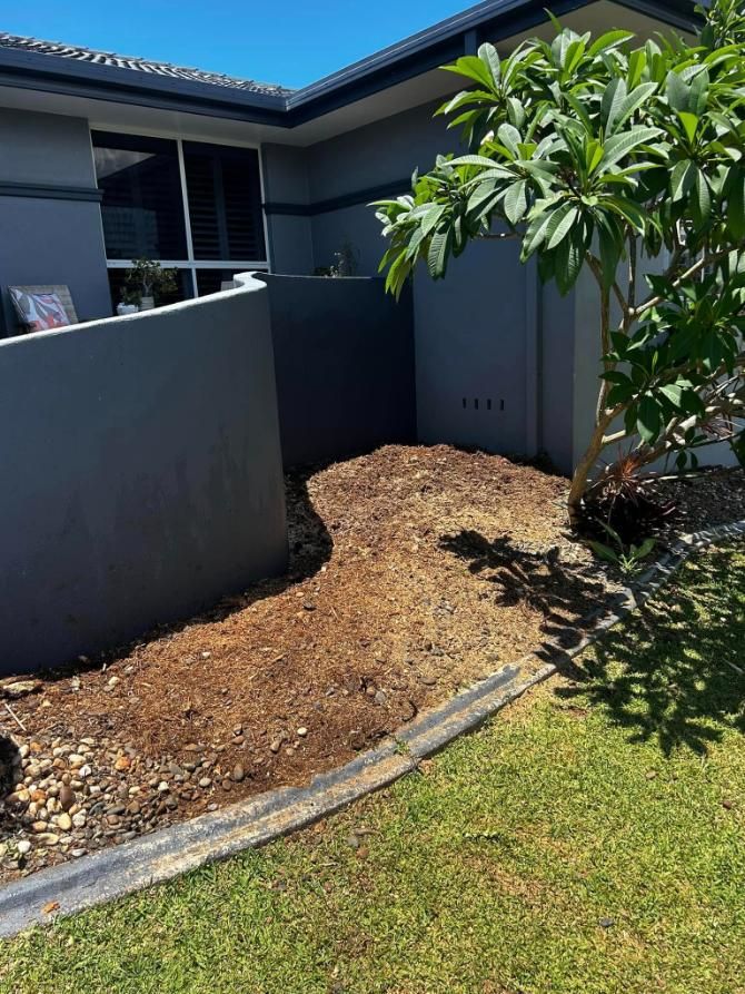 A Person Is Spreading Mulch Around a Plant with A Shovel — All One Arb Tree Service In Bonny Hills, NSW