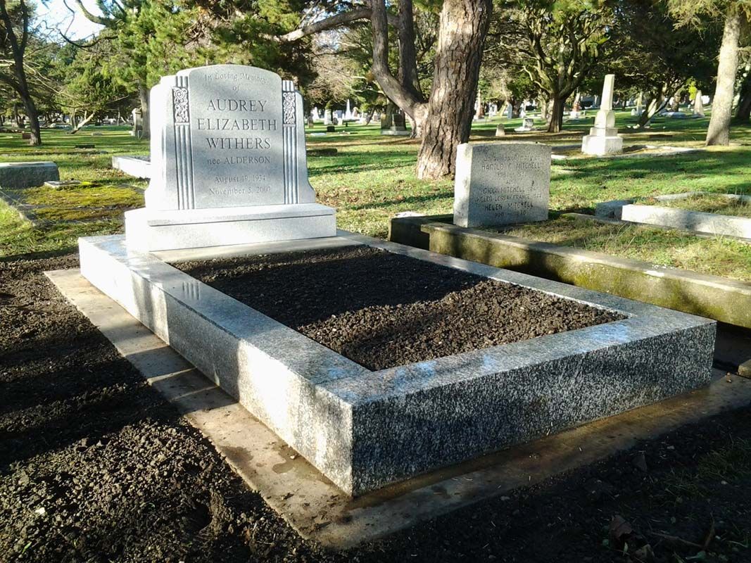 a grave in a cemetery with trees in the background