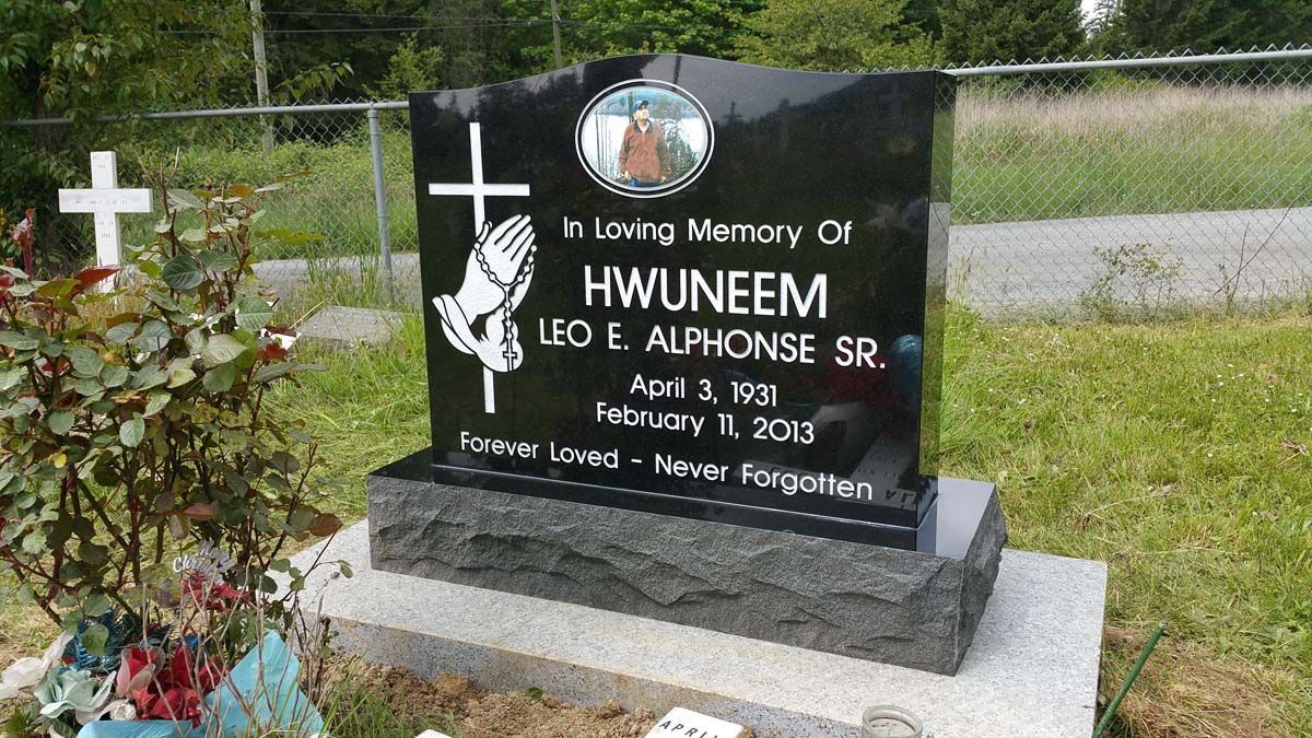 a black gravestone with a cross on it is in a cemetery .
