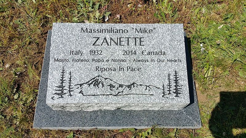 A gravestone in a cemetery with a mountain and trees on it.