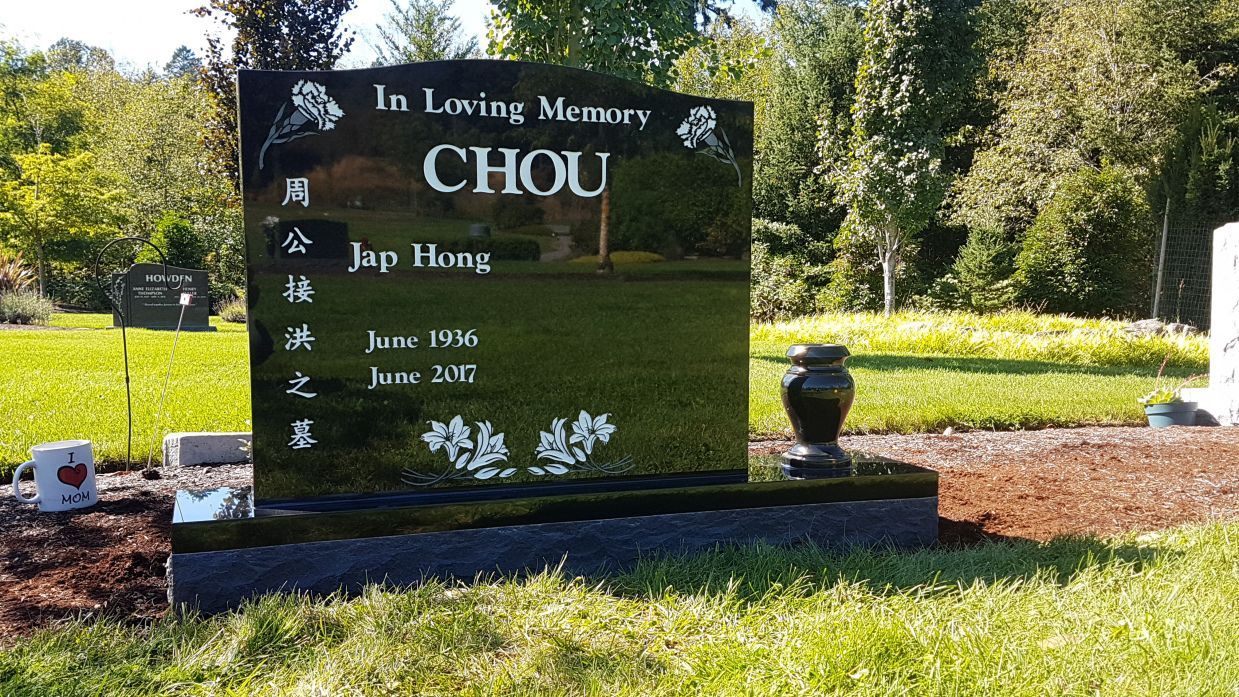 a gravestone for chou is sitting in the grass in a cemetery .