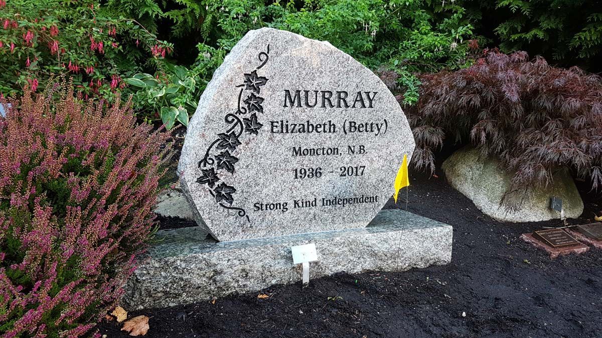 A gravestone for murray is surrounded by trees and bushes in a garden.