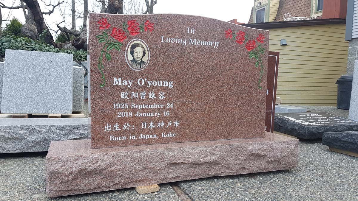 A gravestone with a picture of a man on it is sitting on the sidewalk.