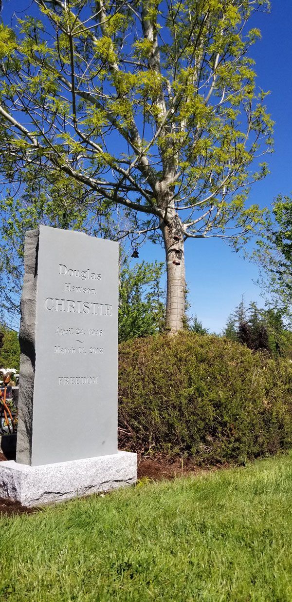 A gravestone in a cemetery with a tree in the background.