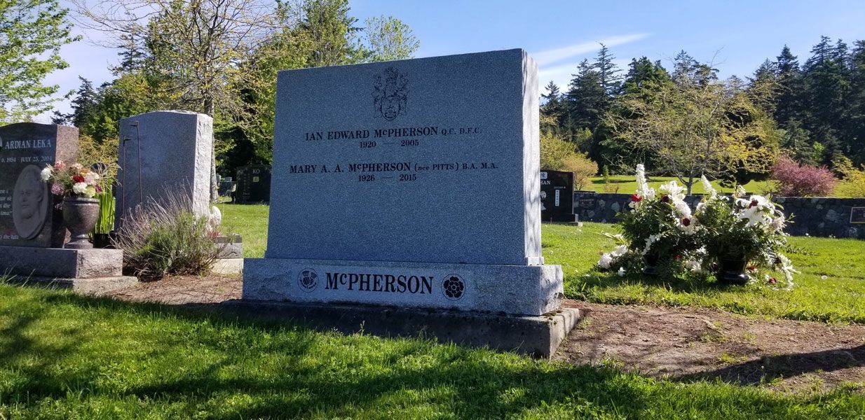 A gravestone in a cemetery with trees in the background.