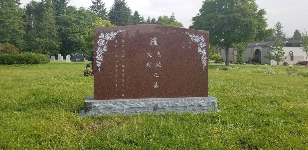 a red gravestone is sitting in the middle of a grassy field .