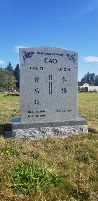a gravestone in a cemetery with chinese writing and a cross on it .
