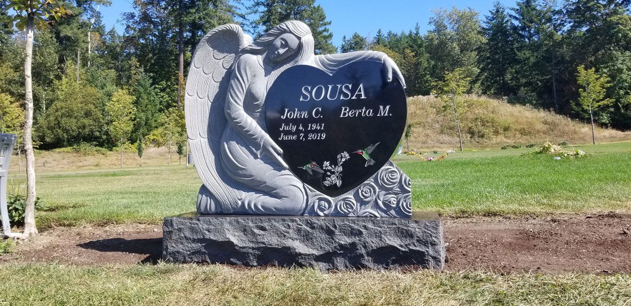 a gravestone with a heart and an angel on it in a cemetery .