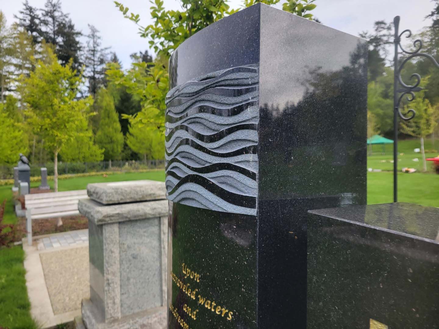 a black granite monument in a cemetery with trees in the background