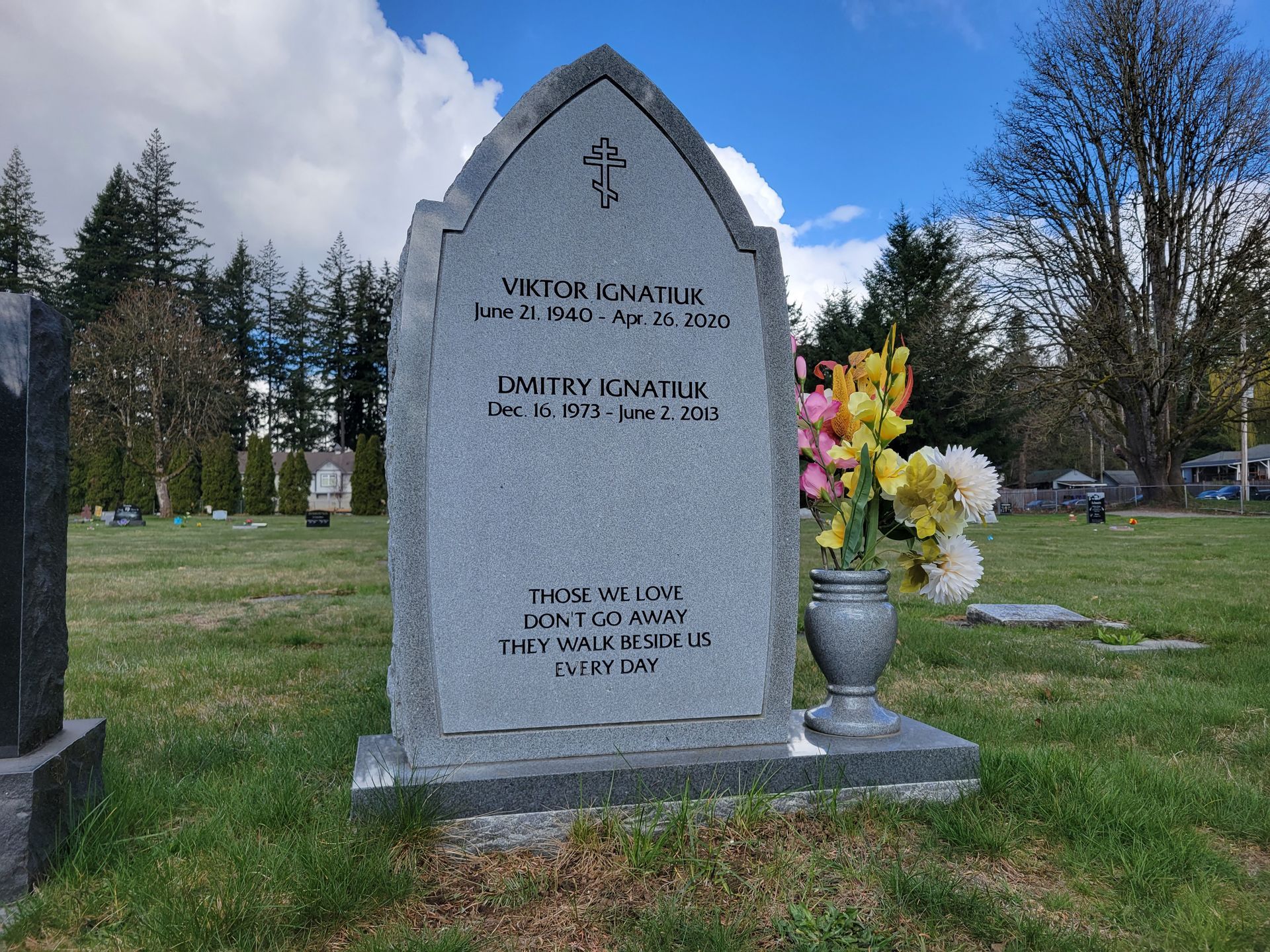 a gravestone in a cemetery with flowers in a vase .