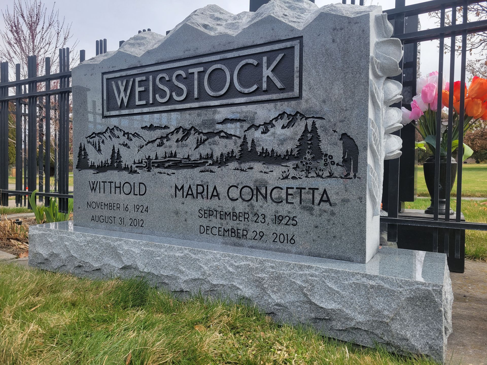 a gravestone in a cemetery with a fence in the background .