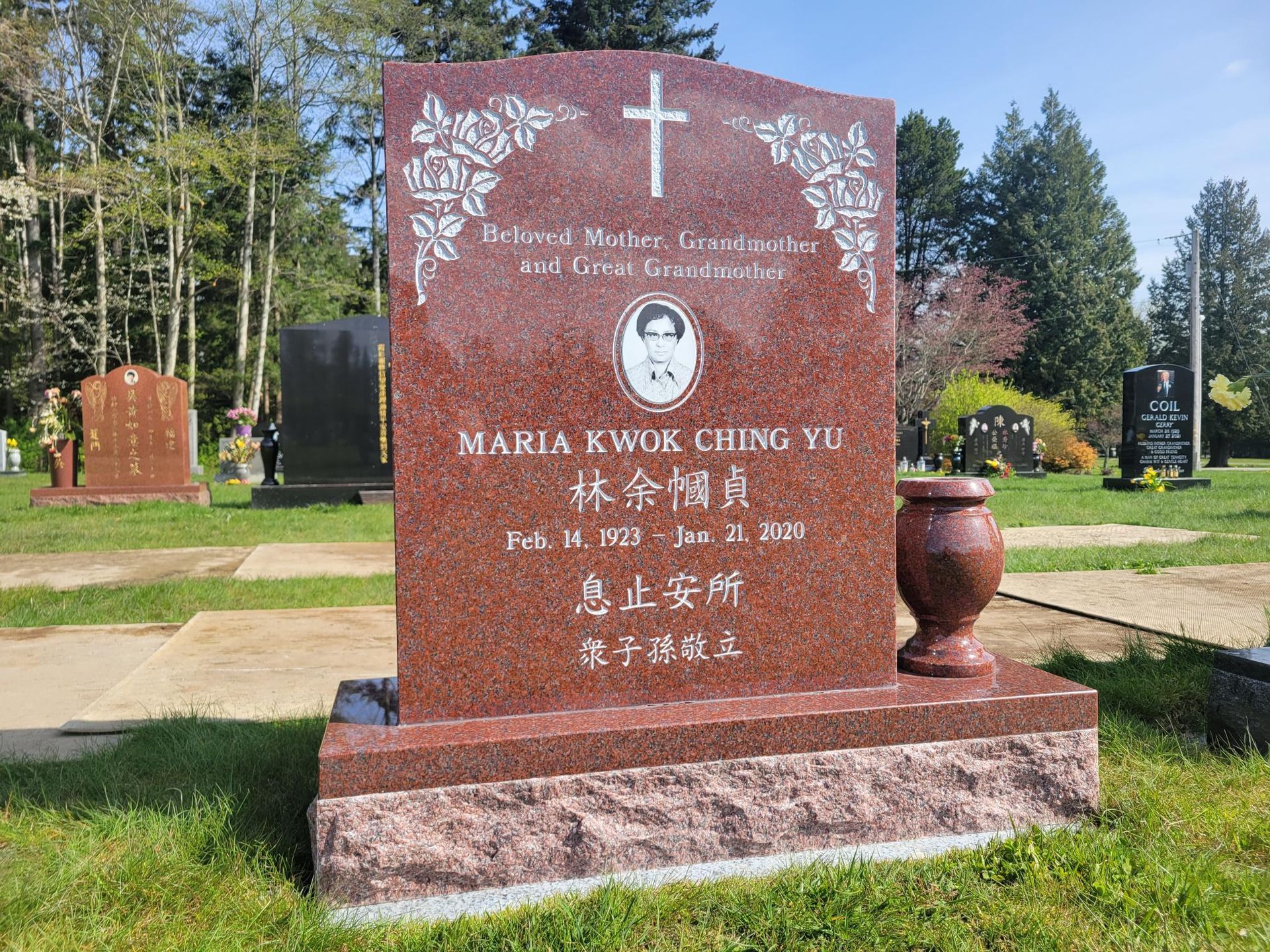 a red gravestone with a cross on it is in a cemetery .