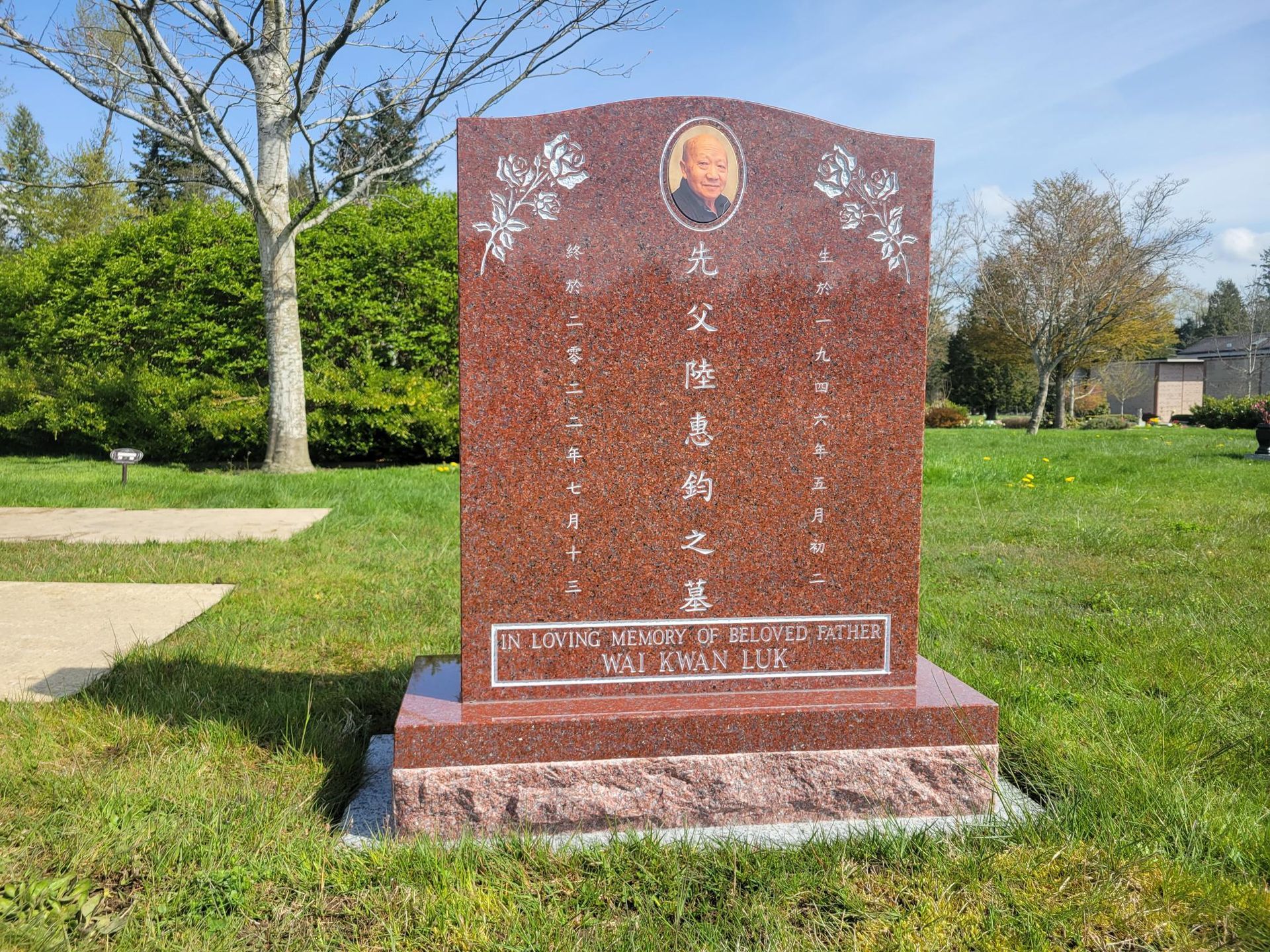 a large red gravestone is sitting in the middle of a grassy field .