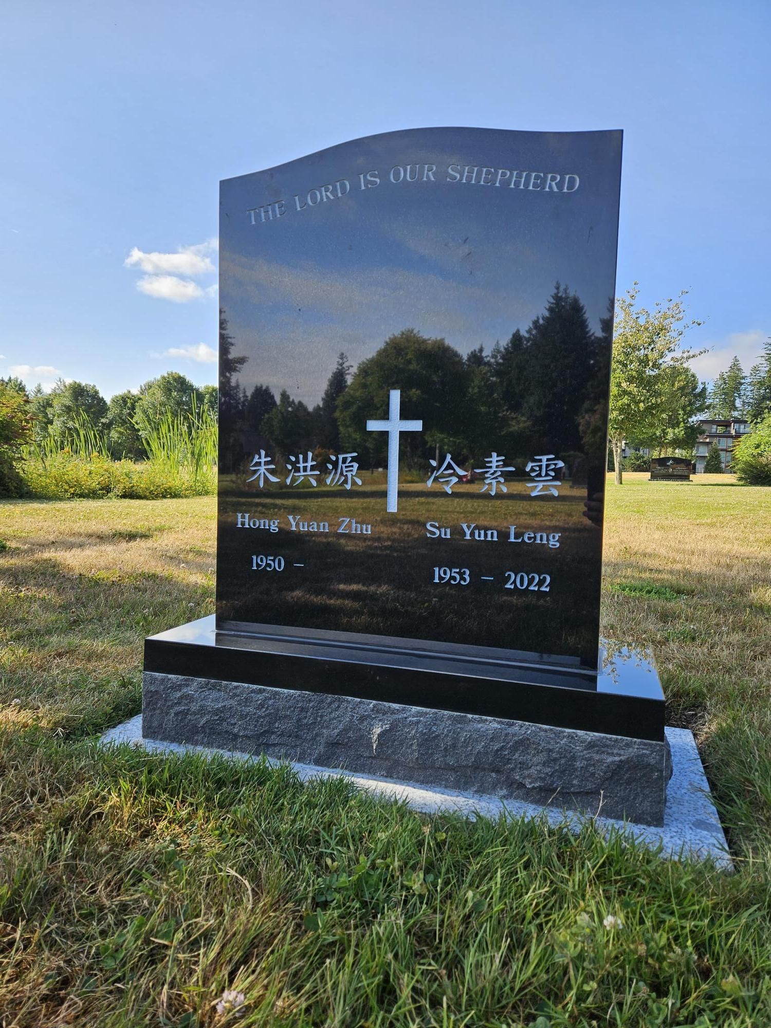 a black gravestone with a cross on it is in a grassy field