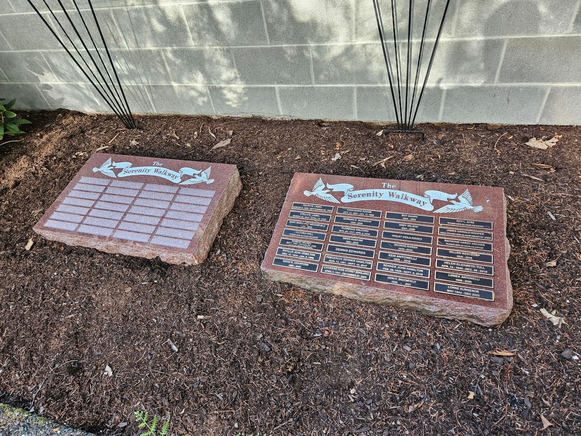 Two plaques are sitting in the dirt in front of a brick wall.