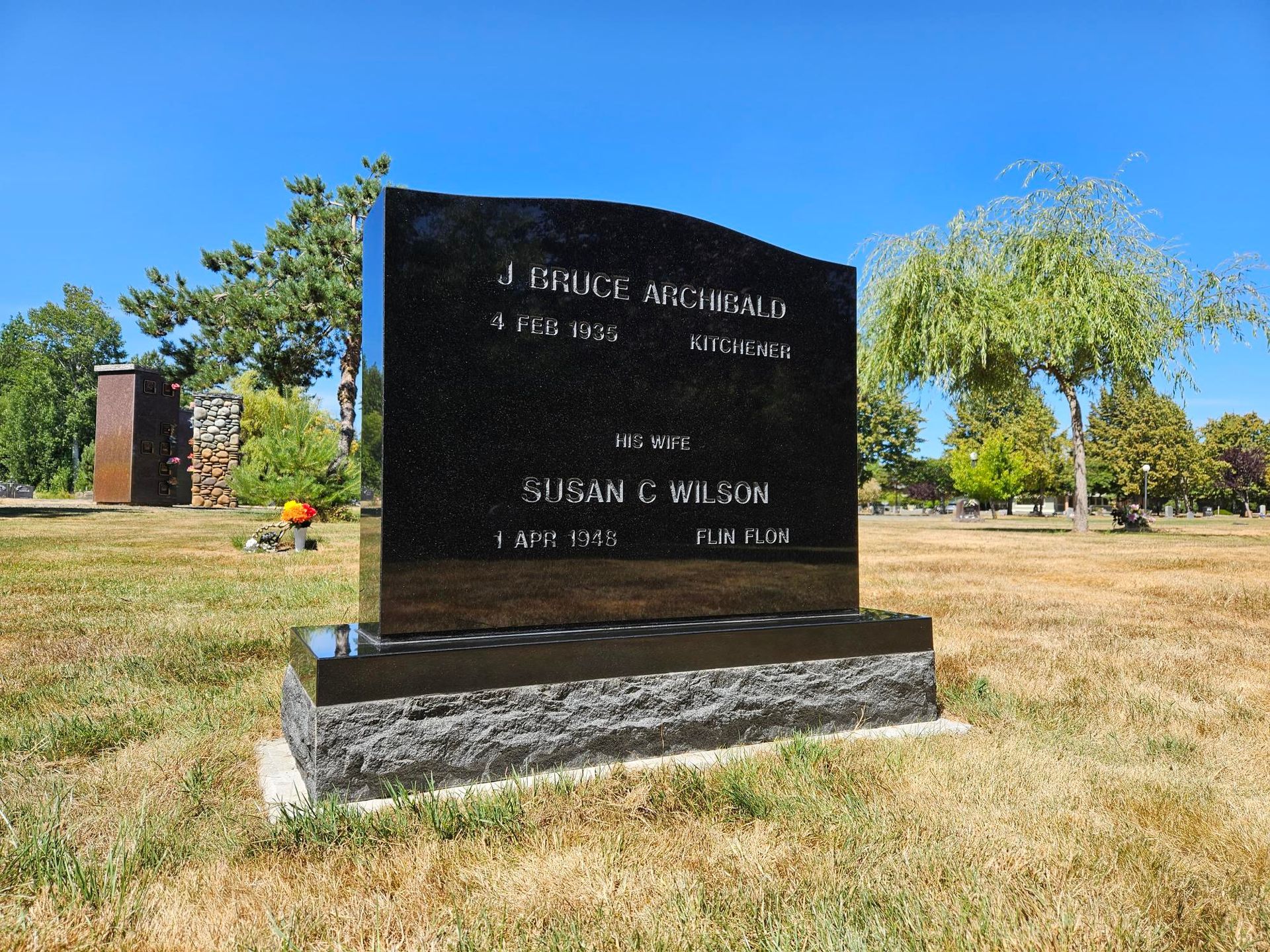 a black headstone in a grassy field