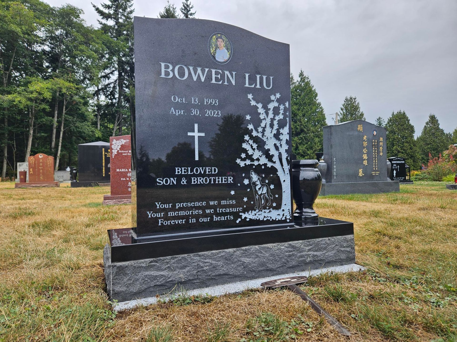 a black grave stone with a cherry blossom tree and wolf 