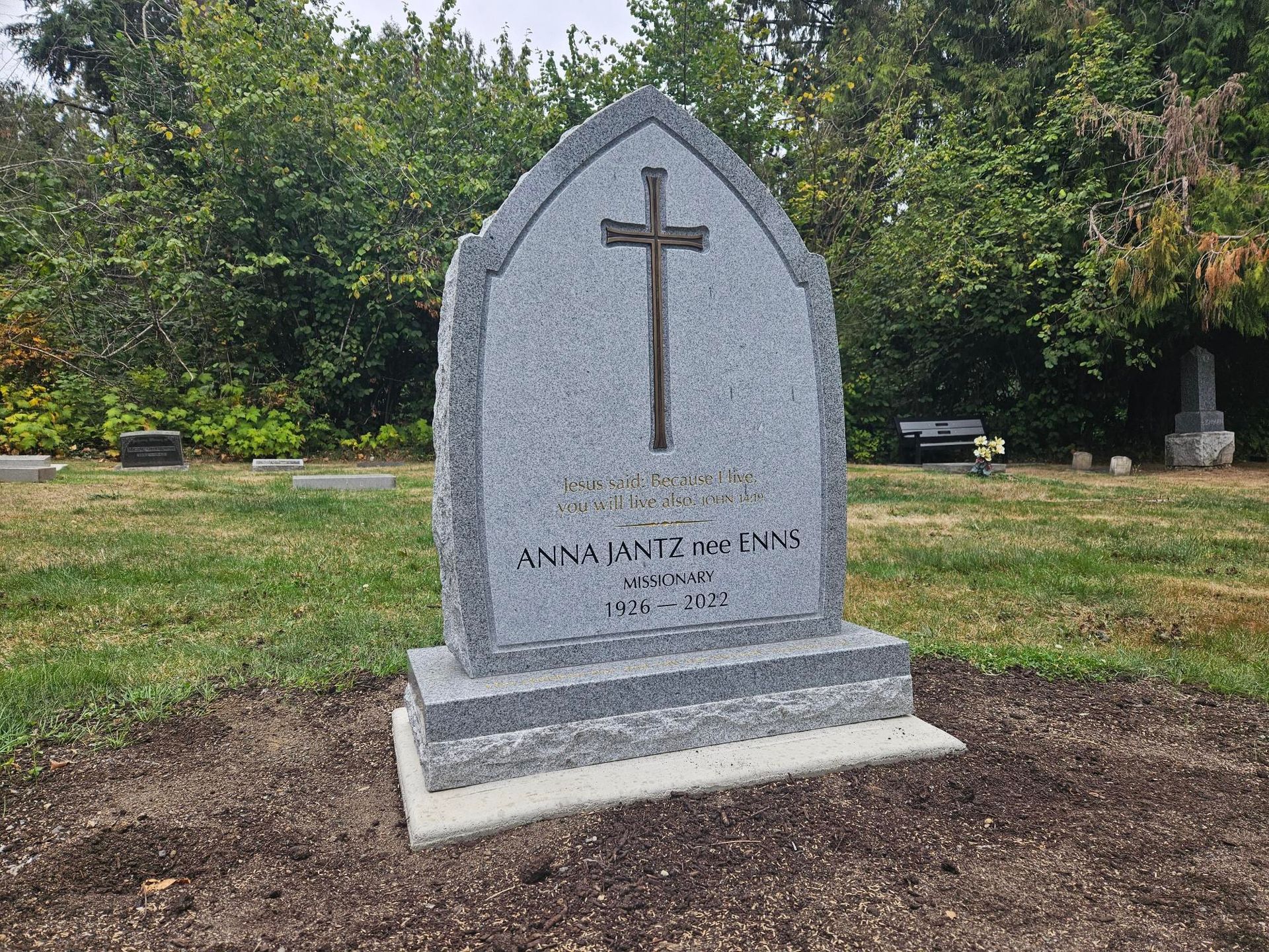 a gravestone with a cross on it in a cemetery .