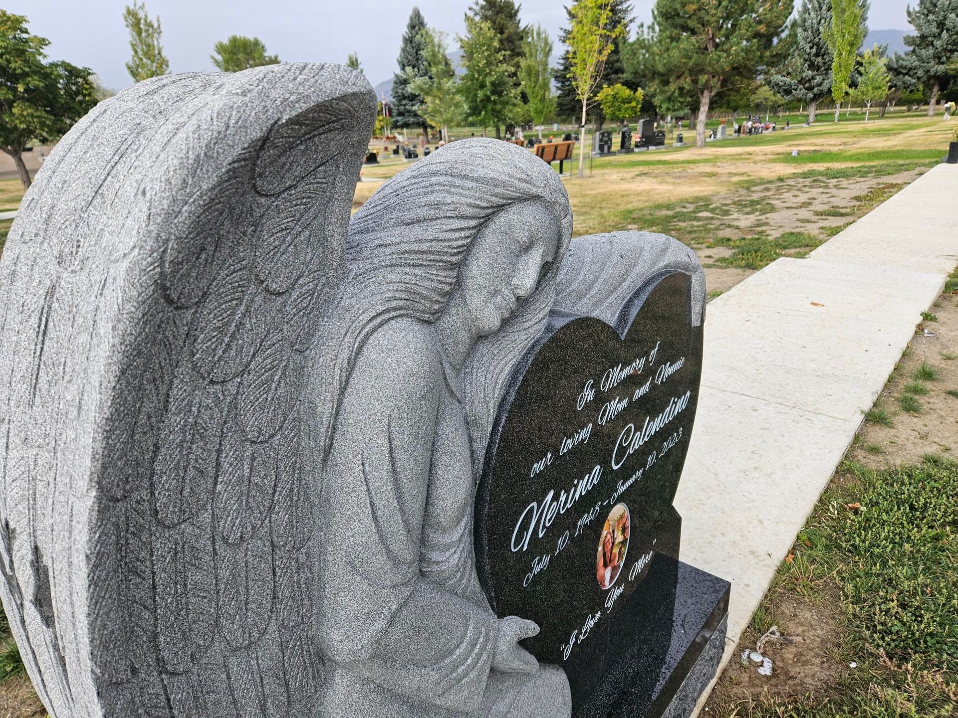 a gravestone with a statue of an angel on it in a cemetery .