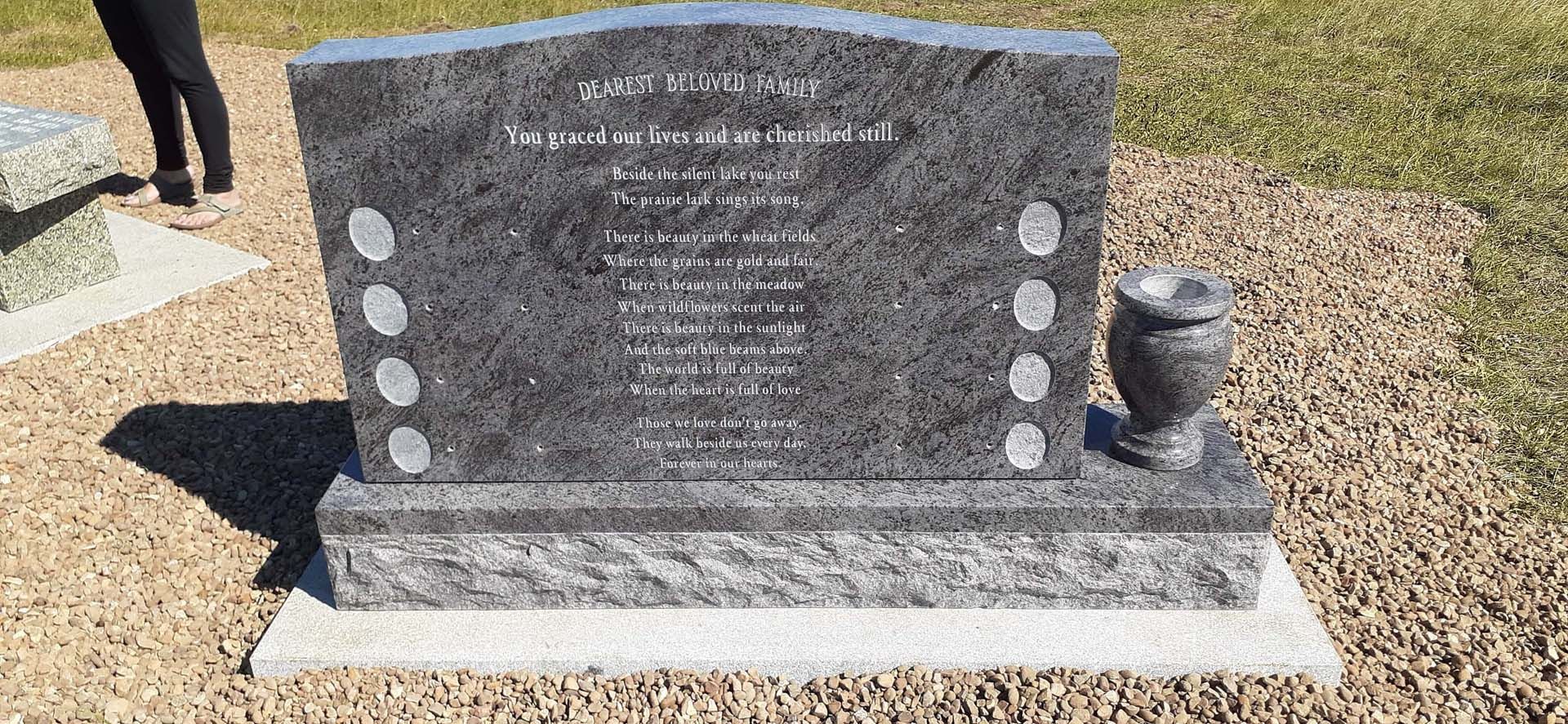a gravestone with a vase in front of it in a graveyard .