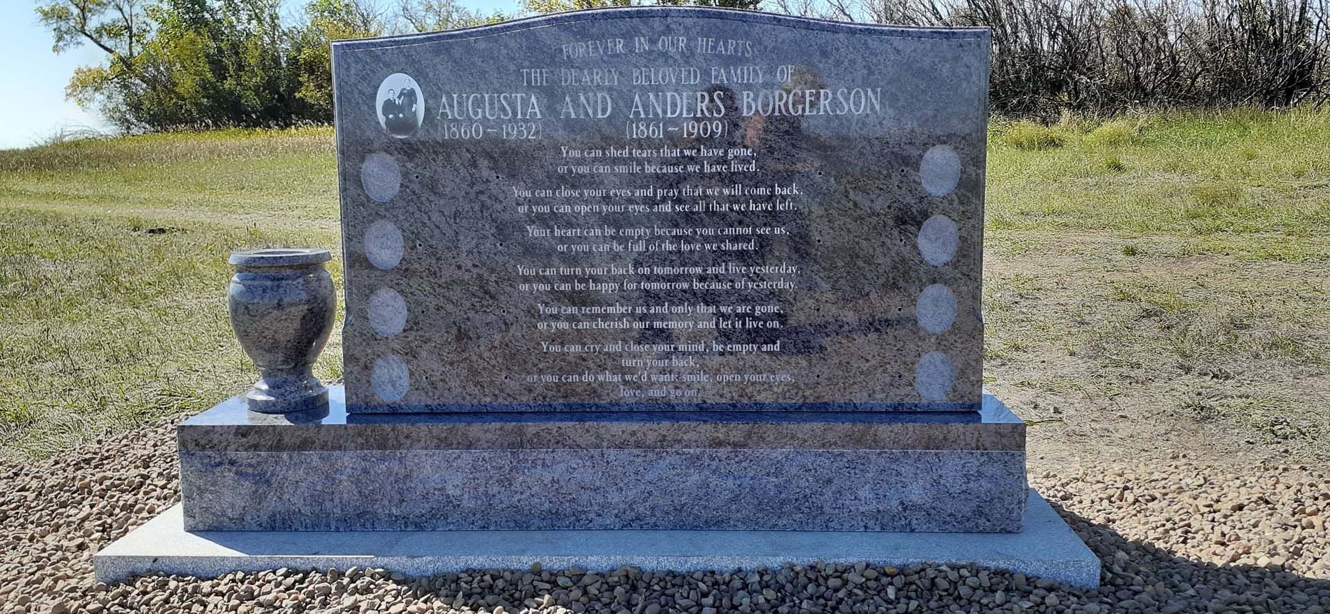 a gravestone with a vase on top of it in a field .