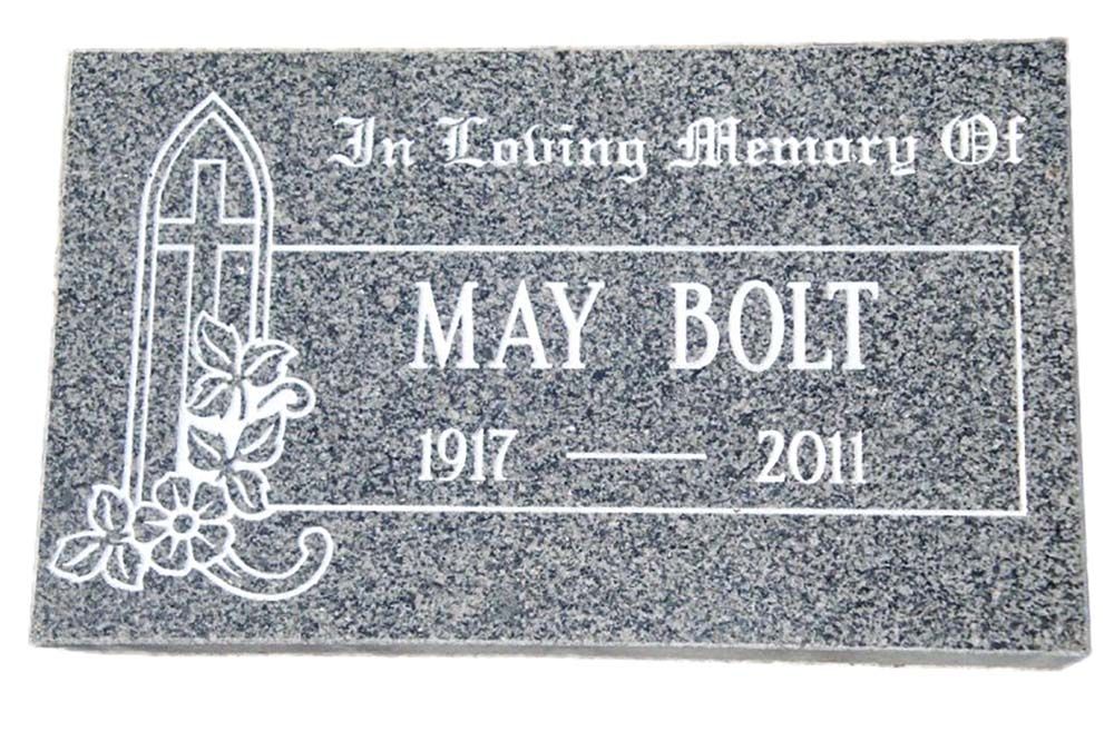 A gravestone for may bolt with a cross and flowers on it.
