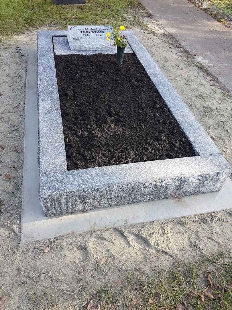 a grave with a vase of flowers in it in a graveyard .