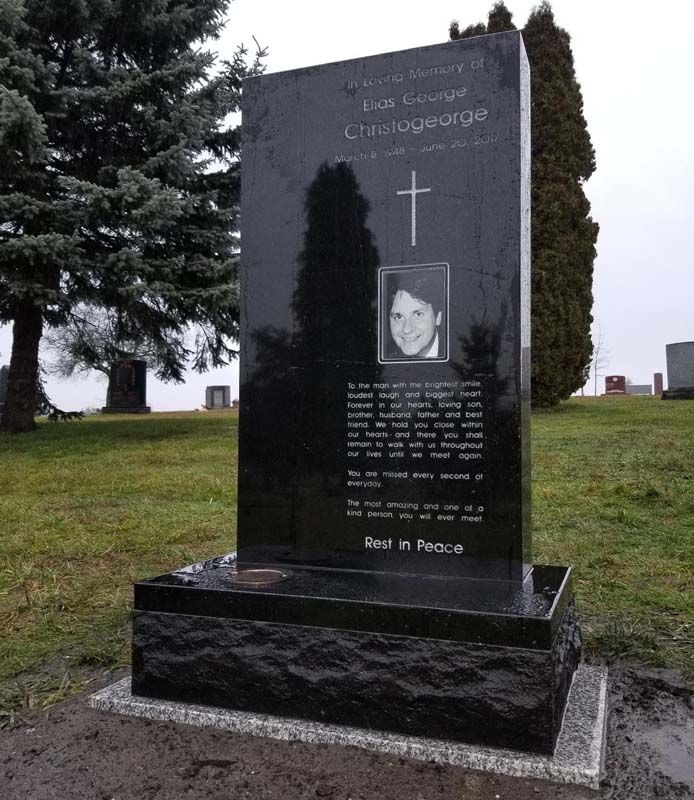 A black monument with a picture of a woman and the words end in peace