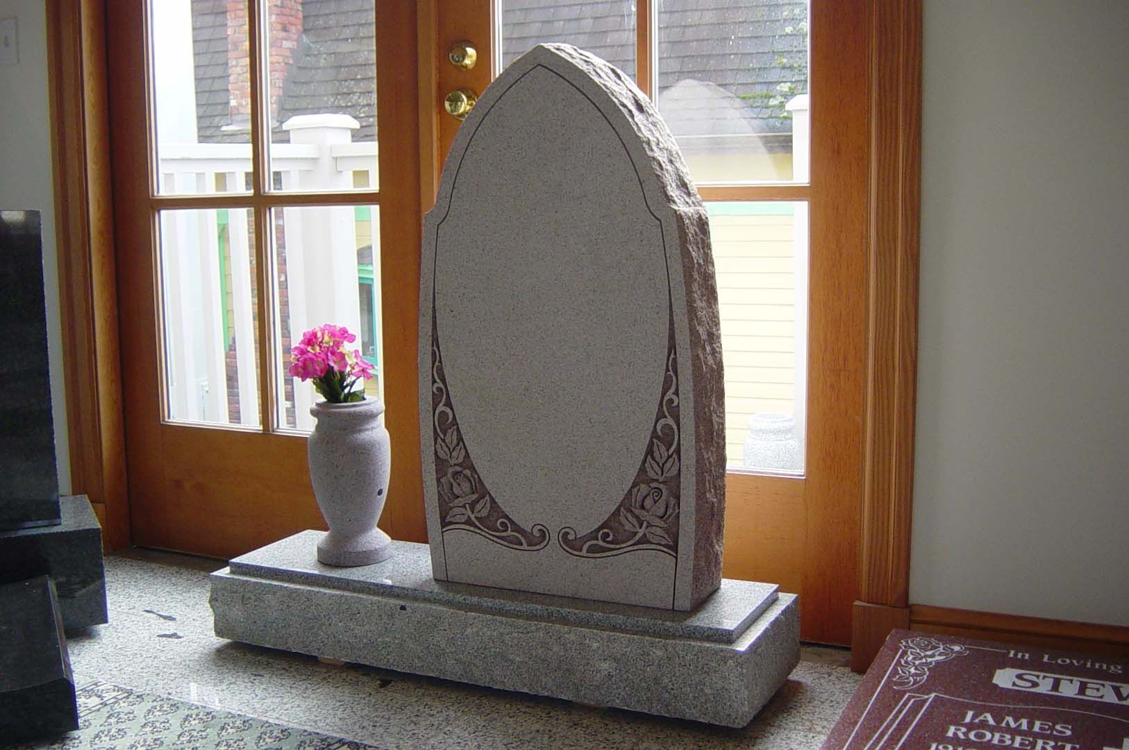 a gravestone with a vase of flowers in front of a door