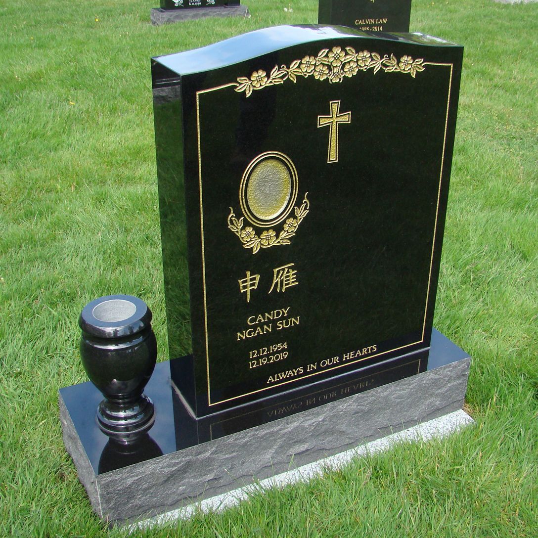 a black gravestone with a gold cross on it