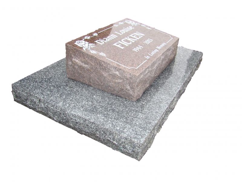A gravestone is sitting on top of a granite slab.
